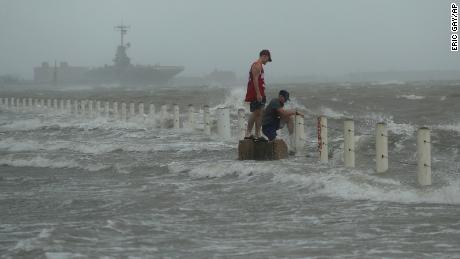 Dos hombres se paran cerca de un malecón mientras el huracán Hanna toca tierra.