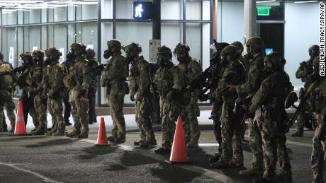 Los oficiales federales se destacan con los manifestantes después de limpiar las calles con gases lacrimógenos afuera del juzgado federal en el centro de Portland la madrugada del sábado.