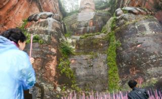 Turistas queman ofrendas a los pies del Buda Gigante en 2016