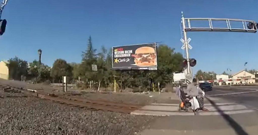 El video muestra a un oficial de policía sacando a un hombre en silla de ruedas de las vías del tren antes de que llegue el tren.